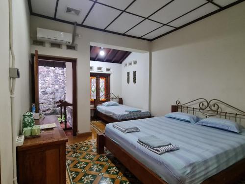 a bedroom with two beds and a desk and a window at Omah Pitoe Yogya Homestay in Yogyakarta