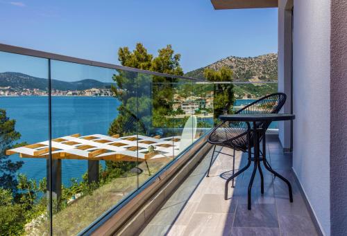 a balcony with a table and chairs and a view of the water at Villa Regina with heated pool and sea view in Marina