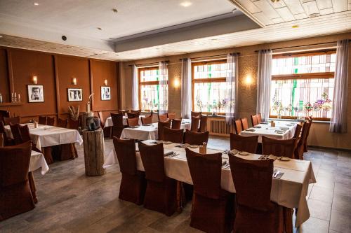 a dining room with tables and chairs and windows at Hotel Fronhof Mettendorf in Mettendorf