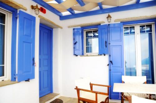 een kamer met blauwe deuren en een tafel en stoelen bij Karyatides Apartments in Kariá
