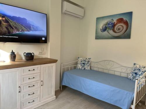 a bedroom with a bed and a flat screen tv at Reginas Studios & Apartments- Blue Flower apartment in Fiskardho