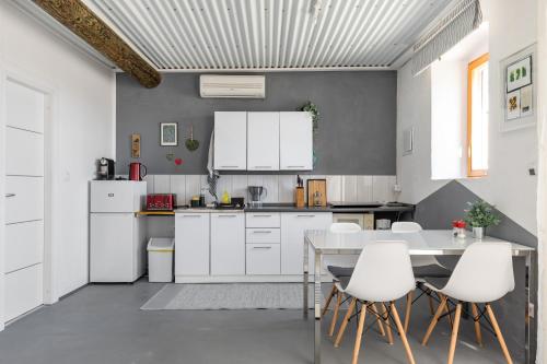 a kitchen with white cabinets and a table and chairs at Waterview Apartments - Koru Apartment and pool in Mimice