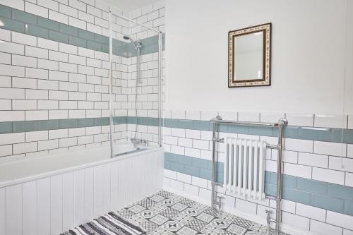 a bathroom with a tub and a mirror and a rug at Poets Cottage in Skinningrove