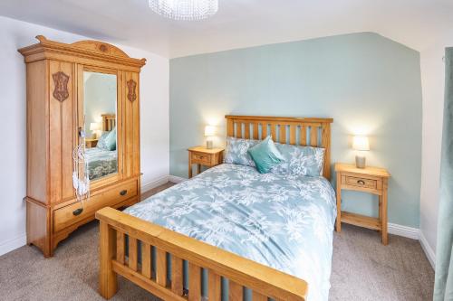 a bedroom with a wooden bed and a large mirror at Poets Cottage in Skinningrove