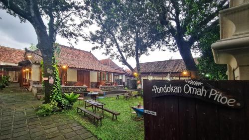 a sign in a yard with benches and trees at Omah Pitoe Yogya Homestay in Yogyakarta