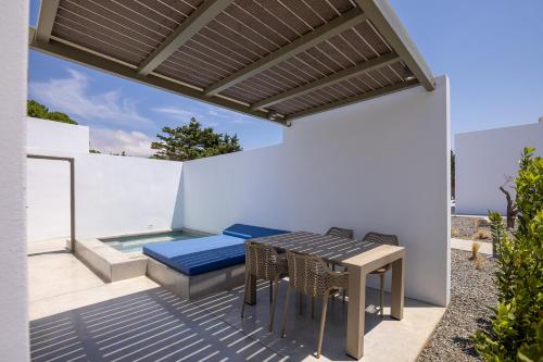 een patio met een tafel en stoelen en een zwembad bij White Holidays Project in Tinos Town