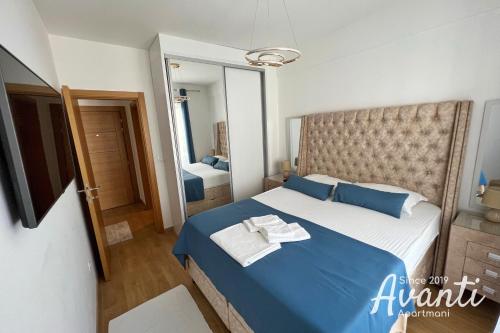 a bedroom with a blue bed and a mirror at Apartmani Avanti Budva in Budva