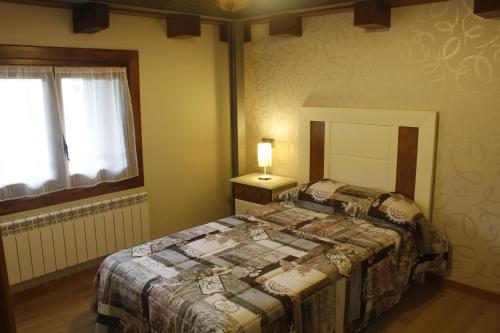 a bedroom with a bed and a lamp and a window at La Casa del Abad in Anguiano