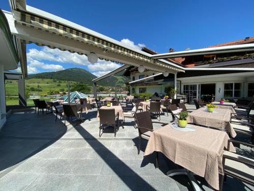 a patio with tables and chairs with mountains in the background at Wohlfühlhotel Berwanger Hof in Obermaiselstein