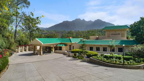 a building with a green roof with mountains in the background at Vivanta Katra Vaishno Devi in Katra