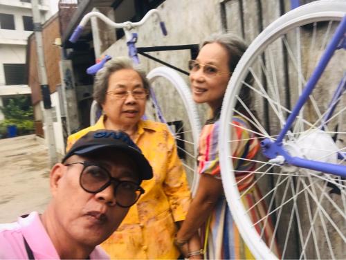 a group of three people standing next to a bike at SolarCell walking street Homestay - โซล่าเซลล์ถนนคนเดินโฮมสเตย์ in Ban Nong Nam Khan