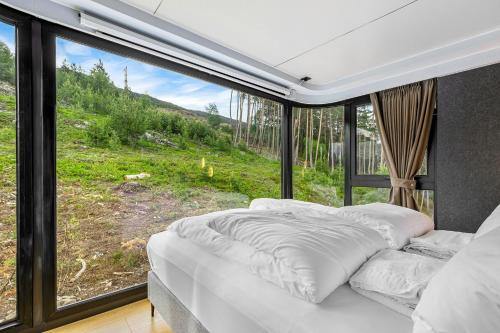 Bett in einem Zimmer mit einem großen Fenster in der Unterkunft Sogndal Fjordpanorama - The atmosphere in Sogndal