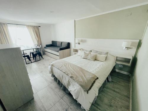 a bedroom with a bed and a couch and a table at Antu Mahuida Apartments in San Carlos de Bariloche