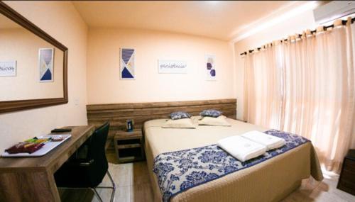Un dormitorio con una cama y un escritorio con toallas. en Open Hotel, en Telêmaco Borba