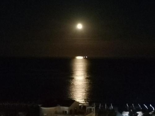 a full moon over the ocean at night at "Красавиците тъмнокоси" Sunset Resort Pomorie in Pomorie
