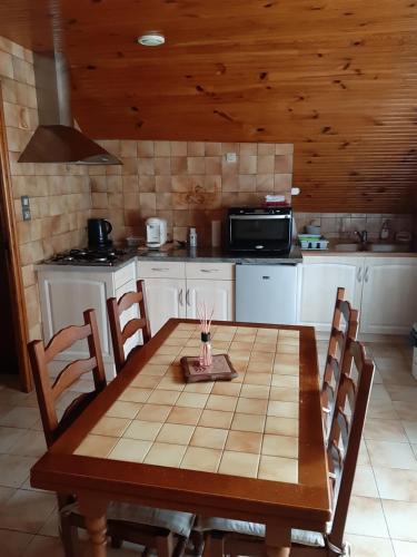 a kitchen with a wooden table with chairs and a microwave at petite maison de montagne avec jardin in Cier-de-Luchon