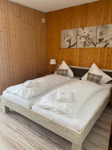マイリンゲンにあるハスリ ロッジの木製の壁の客室で、白い大型ベッド1台が備わります。
