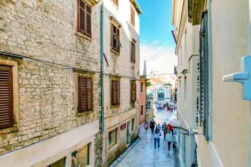 a group of people walking down a street between buildings at Divinity's - old town center in Zadar