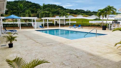 a swimming pool with two blue chairs and a house at Aquamarine Resort-style Vacations in Lucea