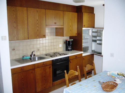 サース・アルマゲルにあるApartment Forestaのキッチン(木製キャビネット、シンク、テーブル付)