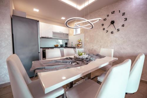 a dining room with a table and a clock on the wall at Apartments Niko in Makarska