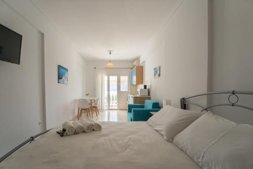 a white bedroom with a bed and a blue chair at Studio Thea in Lixouri