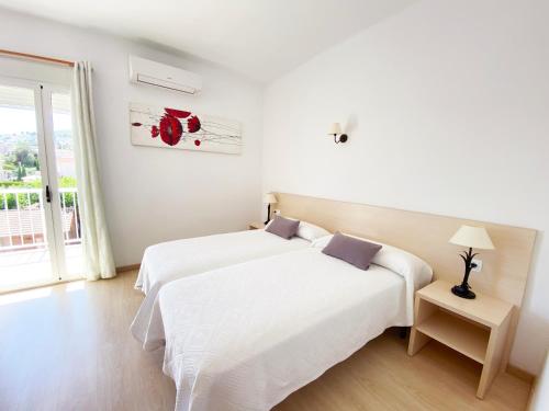 a white bedroom with two beds and a window at Habitaciones Camping Ferrer in Peñíscola