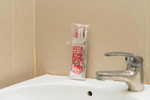 a toothbrush sitting on a sink next to a faucet at RedDoorz at MERR Rungkut Jl Gunung Anyar in Gununganjar