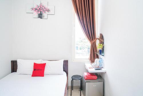 Un dormitorio con una cama blanca con almohadas rojas y una ventana en RedDoorz Plus At Merr Rungkut Jl Gunung Anyar en Gununganjar