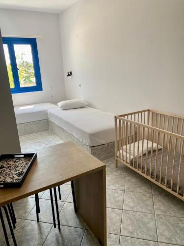 a room with two beds and a table and a crib at Mikes on the beach in Hersonissos