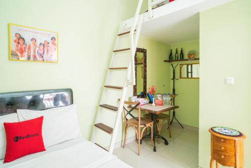 Dormitorio con cama y escritorio con escalera en RedDoorz Syariah near Suncity Mall Sidoarjo, en Sidoarjo