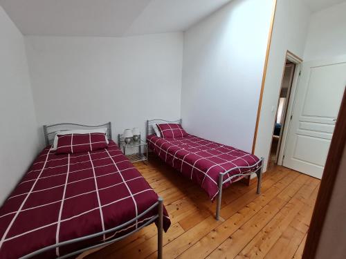 a bedroom with two beds and a wooden floor at La Maison des Grands Bambous - L'Angoumois L'Aunis La Saintonge La Boutonne in Louzignac