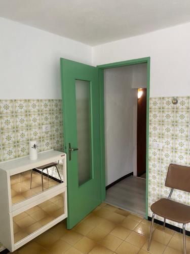 a green door in a room with a table and a chair at Villa Verde in Valsolda