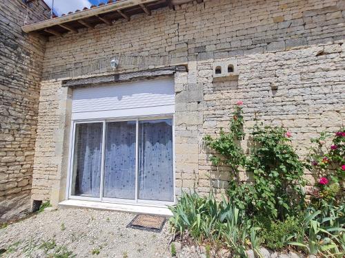 a brick building with a window with a curtain at La Maison des Grands Bambous - L'Angoumois L'Aunis La Saintonge La Boutonne in Louzignac