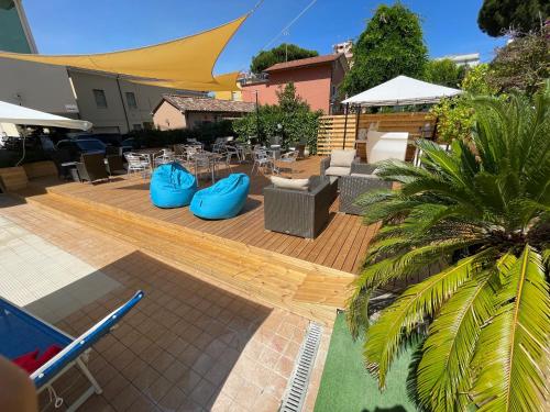 een patio met blauwe stoelen en tafels en een palmboom bij Hotel Apogeo in Rimini