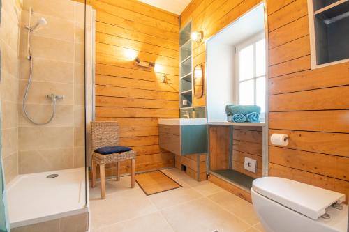La salle de bains est pourvue de murs en bois, d'une douche et de toilettes. dans l'établissement Superbe Appartement Calme 85m², à deux pas du Centre, à Nantes