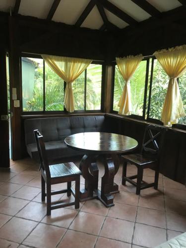 a dining room with a table and chairs and windows at FLOR DE PARAISO BUNGALOWS in Montezuma