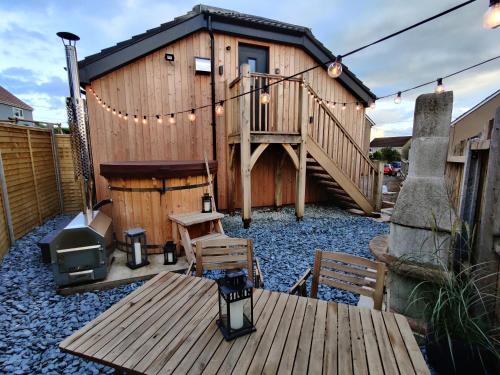a small wooden house with a deck and a grill at The Studio Cheddar - With Wood Fired Hot Tub, Near Cheddar Gorge in Draycott