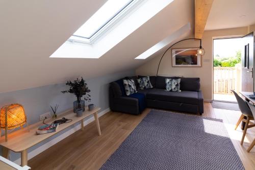a living room with a black couch and a skylight at The Studio Cheddar - With Wood Fired Hot Tub, Near Cheddar Gorge in Draycott