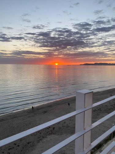 a sunset on the beach with a white fence at Luxury Penthouse with Full Sea View in Durrës