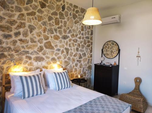 a bedroom with a stone wall and a bed with pillows at Thalassa Apartments & Studios in Kavos
