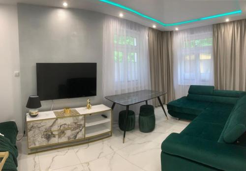 a living room with a tv and a green couch at Apartament Latarników Stilo in Sasino