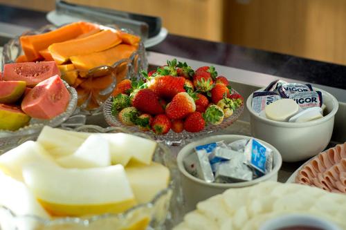 a table with cheese and fruit and other foods on it at Paradiso Peró Praia Hotel in Cabo Frio
