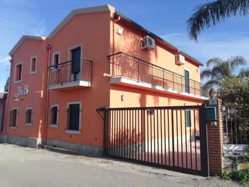 a red and orange house with a black gate at La Casetta B&B in Milazzo