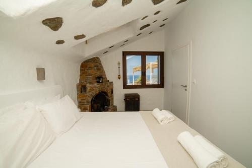 a white bedroom with a large bed and a fireplace at Eternal Blue Kythnos in Mérikhas