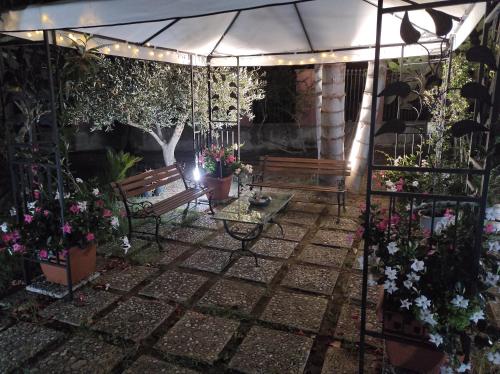 a patio with benches and flowers and an umbrella at La Casetta B&B in Milazzo