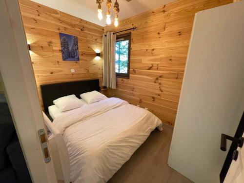 1 dormitorio con 1 cama en una habitación con paredes de madera en Cosy appartement au calme à deux pas du centre, en Auron