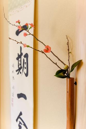 a vase with flowers in it next to a wall at vacation rental SARAKU 茶楽来 in Osaka