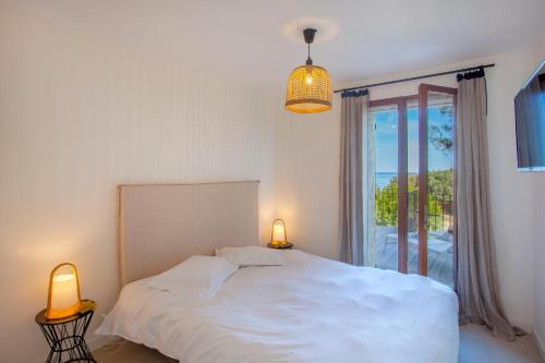 a bedroom with a bed and two lamps and a window at Villa bodri, maison en pierre avec vue mer et piscine chauffée in LʼÎle-Rousse