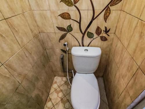 a bathroom with a toilet with a tree on the wall at Kartini Guest House near Alun Alun Probolinggo in Sukobumi